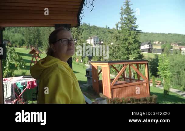 woman yellow hoodie glasses drinking coffee chatting terrace mountain ...