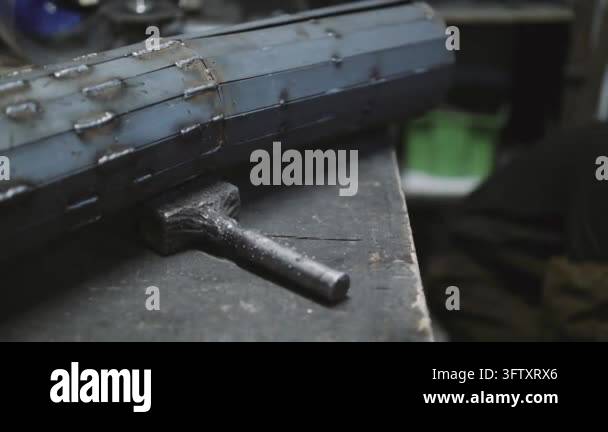 Close-up of a metal object with visible welds resting on a workbench ...