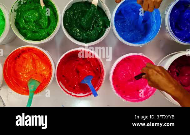 Top view, colorful fabric printing inks in white buckets.Stirring the ...