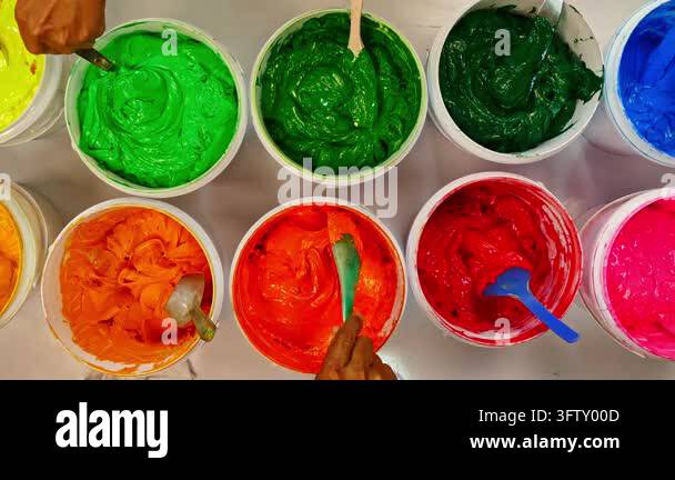Top view, colorful fabric printing inks in white buckets.Stirring the ...