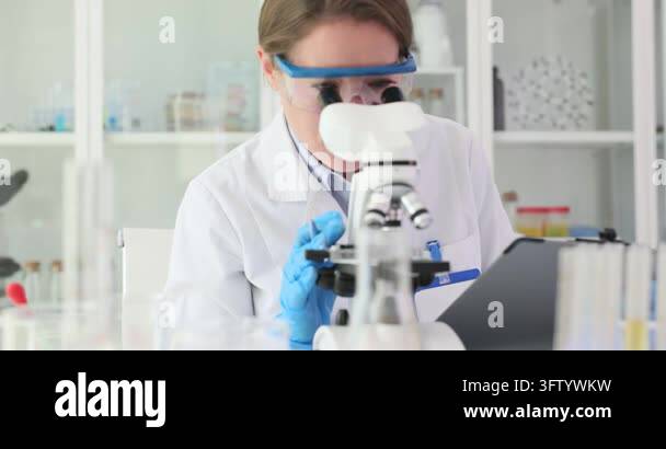 Woman scientist looks in microscope and notices results in lab slow ...