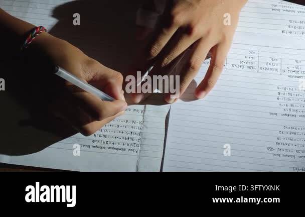Student writing math homework and solving equations in a notebook at ...