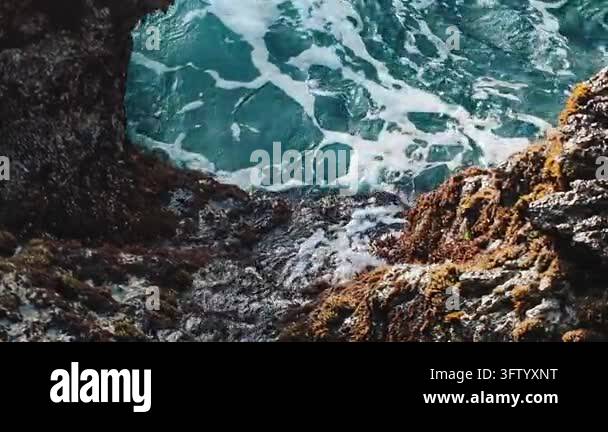 Crystal clear ocean water waves crashing into rocky coastal crevices in ...