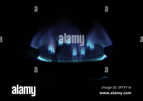 Video of a small blue fire dancing on a gas burner in a dark kitchen ...