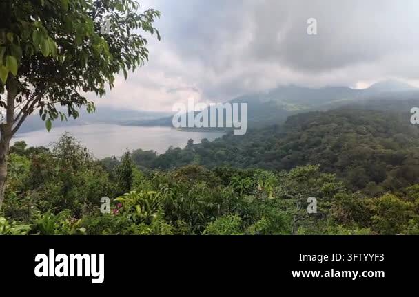 Scenic view of lush green tropical forest, lake, and mountains under a ...