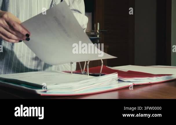 Focused female employee wearing glasses organizing paperwork in a ...