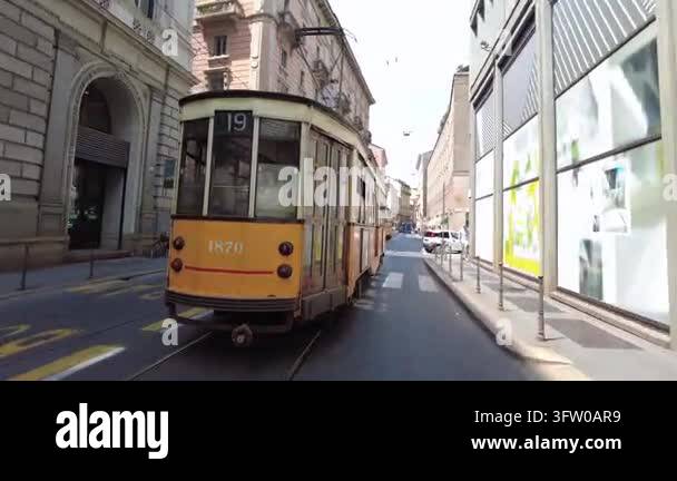 Tracking shot following a vintage yellow tram as it travels down a city ...