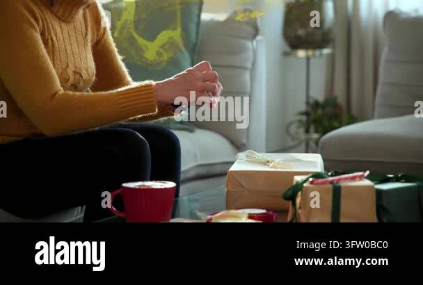 Woman finishing taping holiday gifts, gold effect appearing around ...