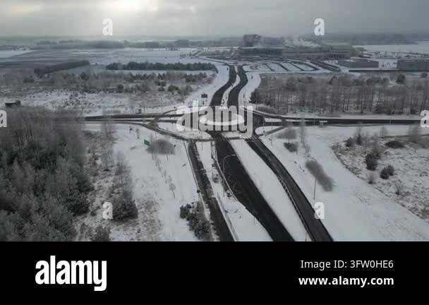 Drone footage moves toward a snow covered roundabout and access road ...