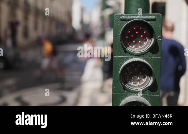 Crossing Light Sign Close-up of a flashing red traffic light with people crossing a sunlit ...