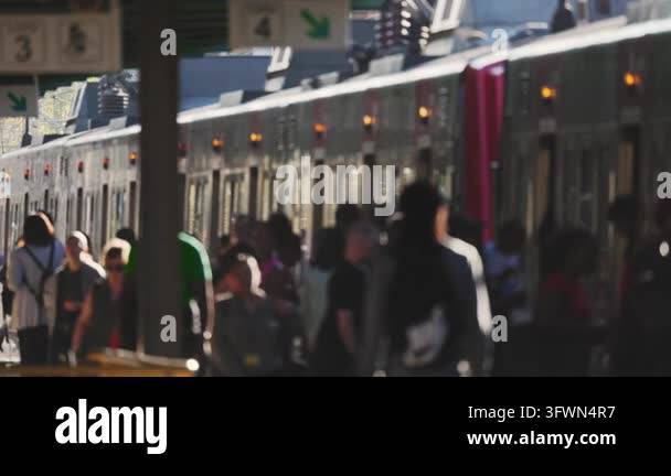 Passengers stand on the platform beside a train at a railway station ...