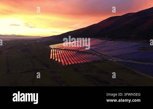 Wwhile Red sunset light bathes a hillside solar farm, Bulgaria. Warm tones ...