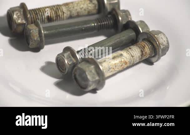 Close-up studio shot of a hand taking away rusty flange hex bolts with ...