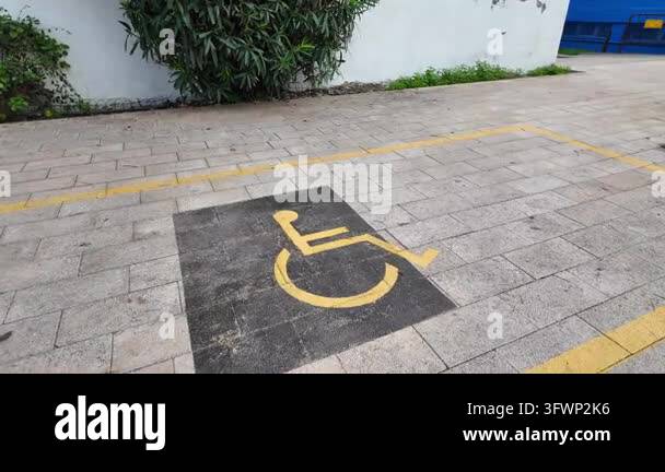Reserved disabled parking space with yellow wheelchair icon on tiled ...