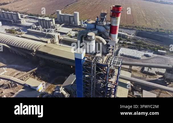 An aerial view shows a power plant with a red and white smokestack ...