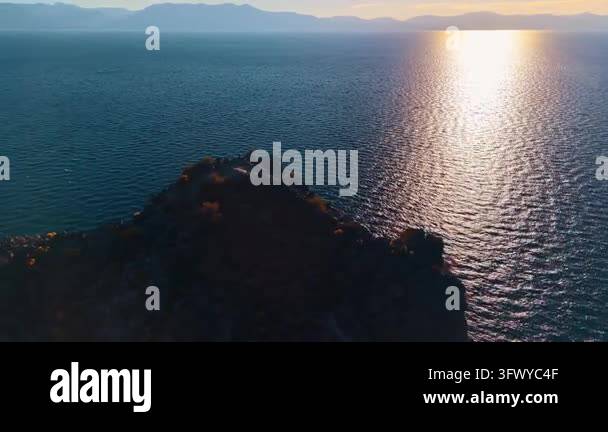 A rocky promontory overlooks the sunlit surface of Lake Tahoe. A broad ...