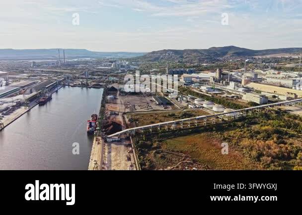 Cargo ships sit beside docks as rail lines, factories, storage tanks ...