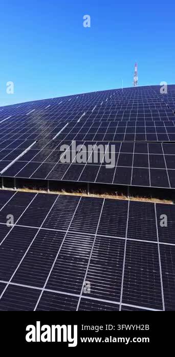Solar panels cover a sloping site, with a communication mast on the ...