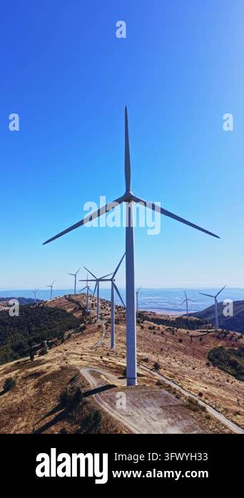 Wind turbines line a ridge in a rural mountain area, with a valley in ...
