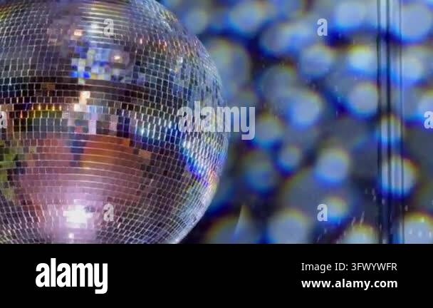 Close up of a spinning disco ball reflecting colorful lights and ...