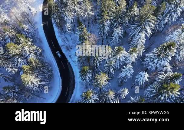 Aerial view of a car driving on a winding road through a snow covered ...