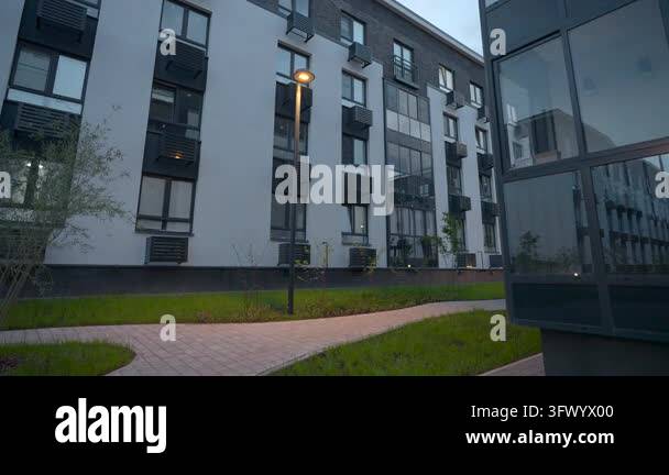 Ground level courtyard view along modern residential building at dusk ...