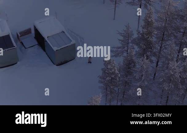 Snow In Athens Top-down rotating view of two snow-covered mirror cabins with a person ...