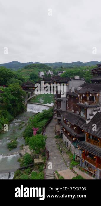 Slow sideways flight along stilt houses and a stone path above river ...