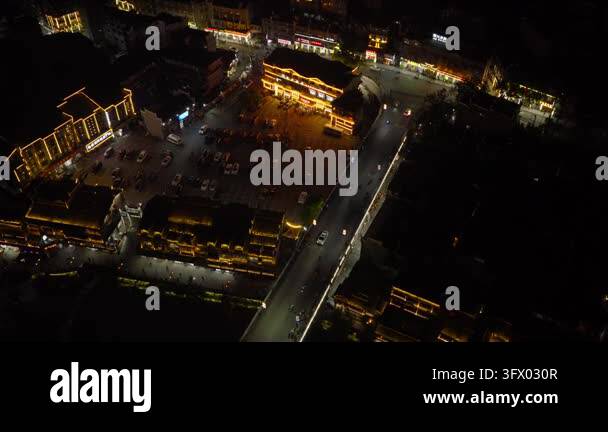 Rotating tilt down to a top-down view of a lit parking lot, road bridge ...