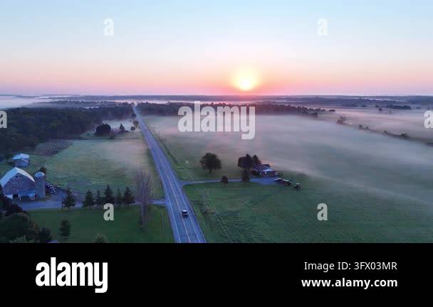 Sunrise over misty fields and winding road Stock Video Footage - Alamy