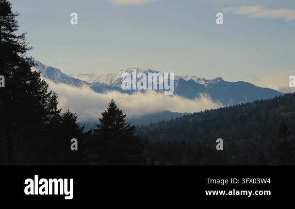 Snow In Athens A wide shot of snow-capped mountains partially obscured by low-lying ...