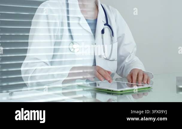 Medical doctor wearing a white lab coat and stethoscope, sitting at a ...