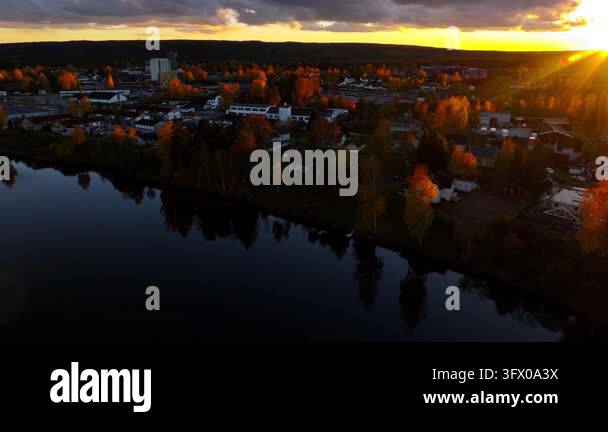 Aerial view of a town by a river during sunset with colorful foliage ...