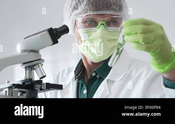 Scientific professional wearing green protective equipment examining ...
