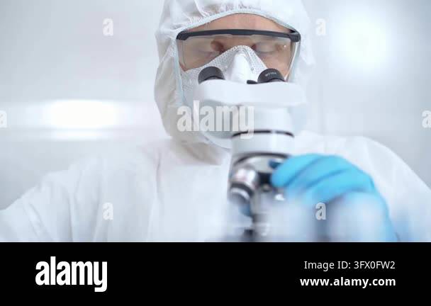 Scientist in ppe analyzing samples using a microscope in a laboratory ...