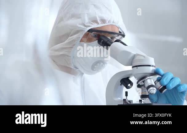 Scientist in ppe analyzing samples using a microscope in a laboratory ...