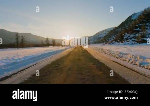 A point of view shot of driving on an empty highway through a snowy ...