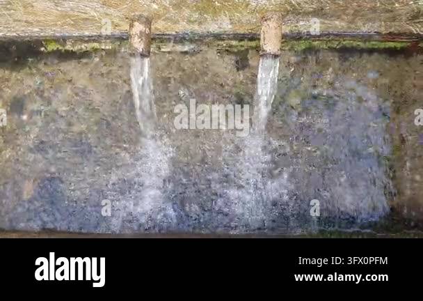 A top-down view shows two metal spouts pouring spring water at a ...