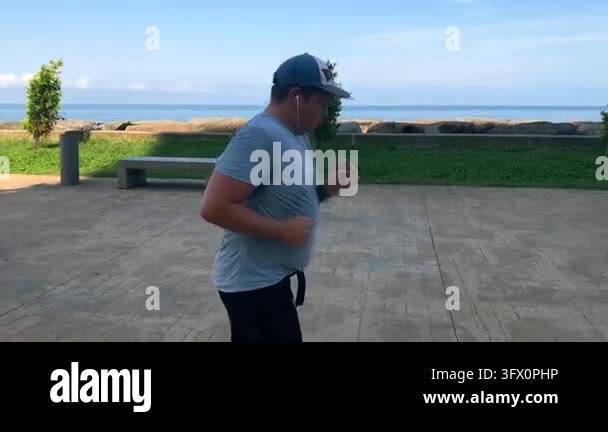 Man jogging along seaside promenade, side view with ocean and ...