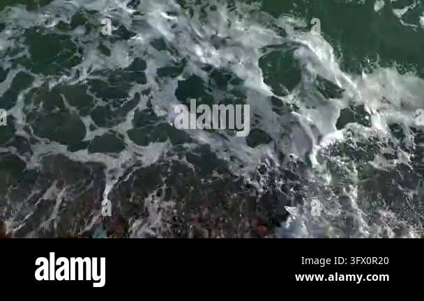 White foam patterns move across dark seawater in a close view ...