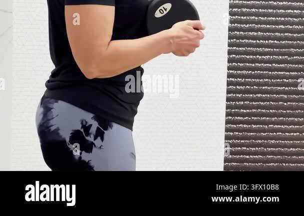 Background For Creative Form Woman performs strength training with a heavy dumbbell in a gym ...