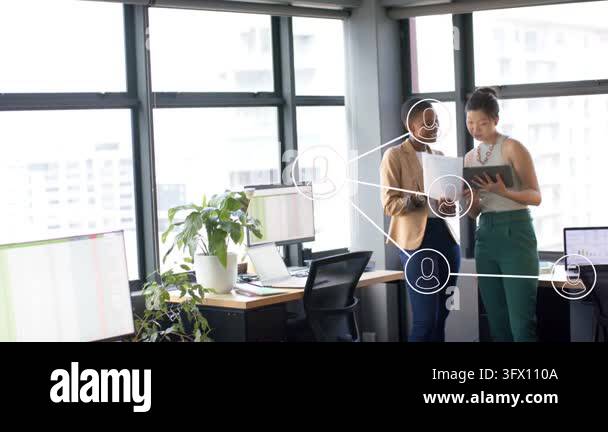 Two women tapping tablet, reviewing papers in office, user icons ...