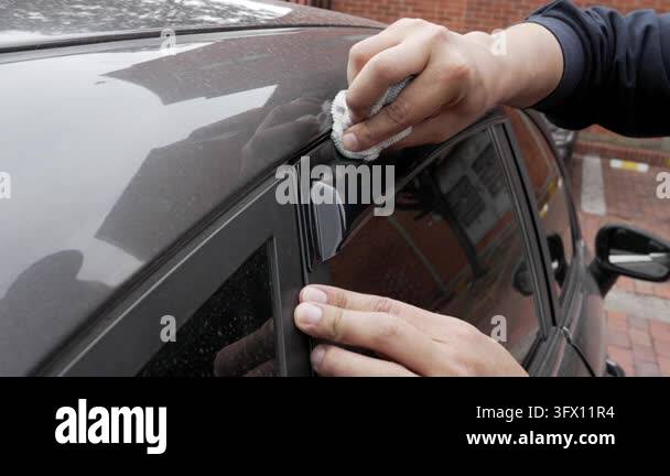 Winiw Frame A person aligns a dark plastic wind deflector above a parked car's side ...