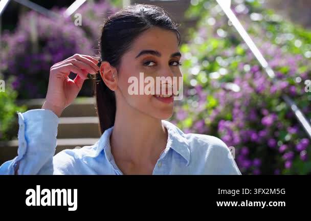Woman In Flowers An Iranian woman in a light blue shirt smiles, tilts her head and ...