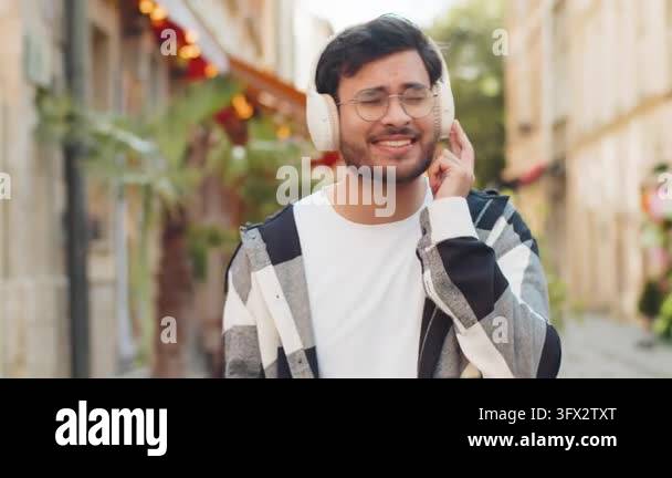 Happy overjoyed Indian man wearing wireless headphones choosing ...