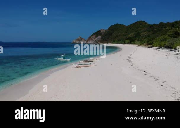 Drone flight along an empty white sand beach with turquoise water and ...