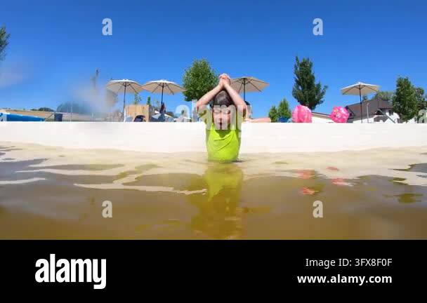 Hawaii Diving Pool Slow motion underwater view of young boy diving into a murky green ...