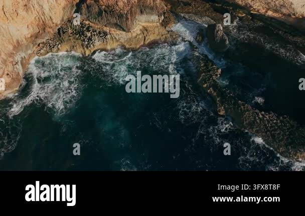 Aerial top view of waves crashing into limestone rocks and cliffs on ...