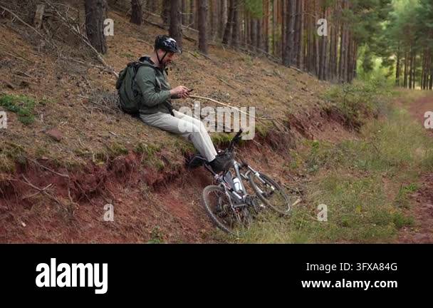 Relaxing in a serene forest, a cyclist rests on the trail, engrossed in ...