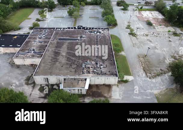 Deteriorating commercial architecture stands dormant amid wild weeds ...